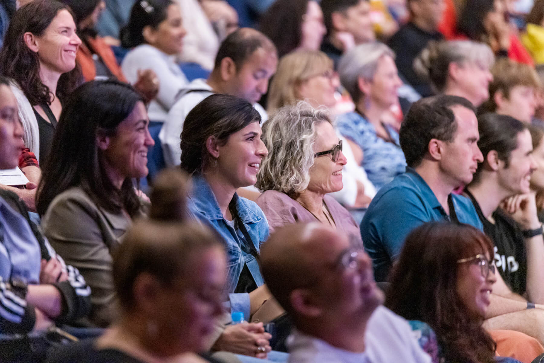 A diverse group of individuals seated in a spacious auditorium, eagerly awaiting an event or presentation.