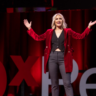 A woman in a red jacket and black pants performing on stage.