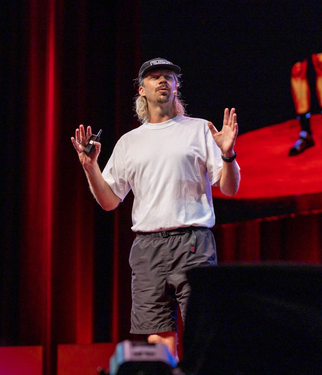 A man standing on a stage with his hands out, appearing confident and ready to address the audience.