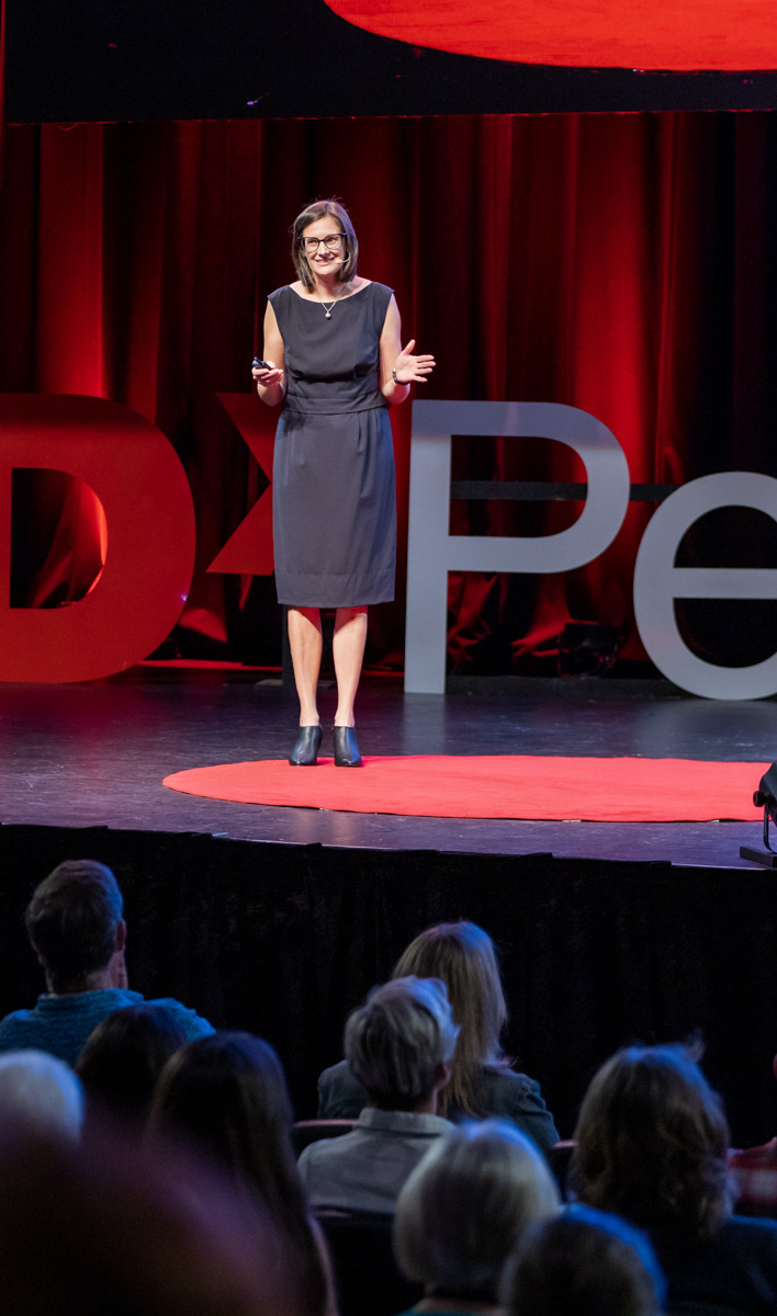 Woman delivering a TEDx talk on stage.